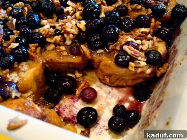 Baked French Toast - A Slice Removed A section of the baked blueberry pecan french toast is missing, showcasing the delicious interior with soaked bread, blueberries, and pecans.