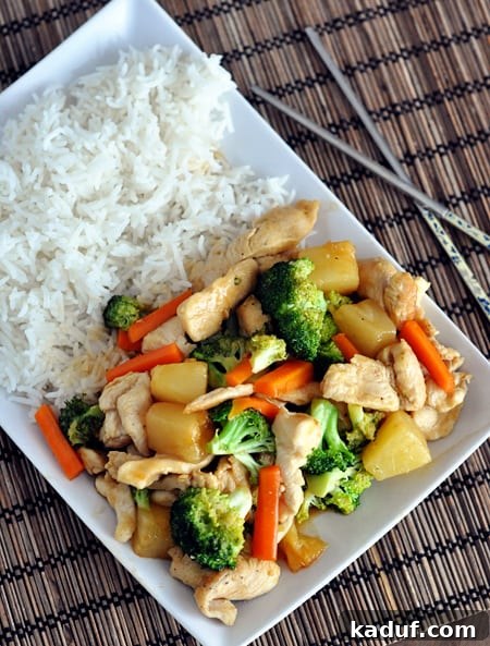 A vibrant Teriyaki Chicken Stir-Fry and fluffy white rice artfully arranged on a rectangular white platter.