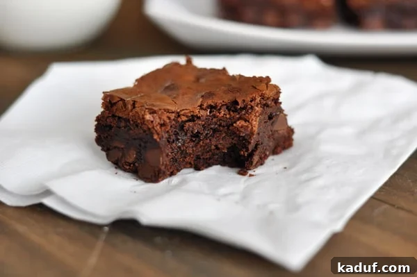 A perfectly baked Tappan Hill brownie with a bite taken out of it, revealing its rich, moist interior, resting on a crisp white napkin.
