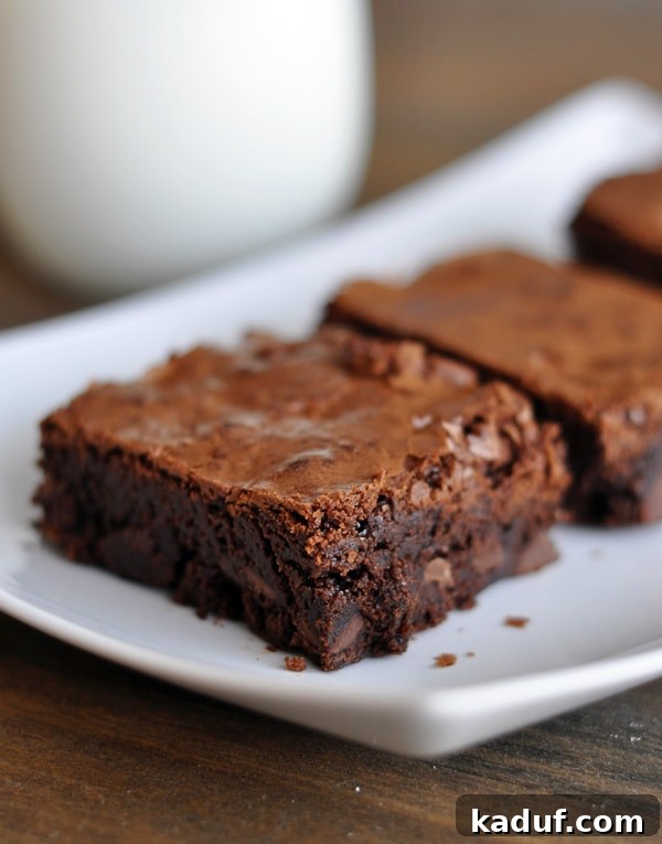 Perfectly cut brownie squares, showcasing their soft texture and rich color, artfully arranged on a pristine white platter.