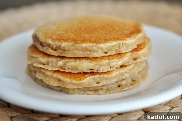 Easy Overnight Cinnamon Oat Pancakes 3 Four stacked pancakes on a white plate.