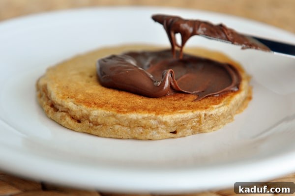Easy Overnight Cinnamon Oat Pancakes 4 A pancake getting covered with Nutella.