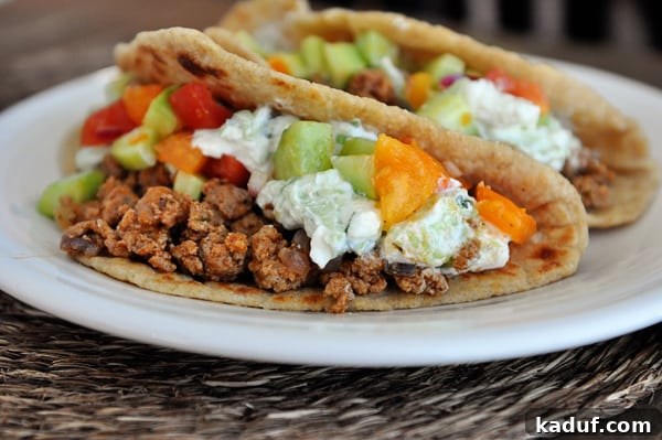 Epic Greek Tacos 5 Two stuffed Greek tacos on a white plate.