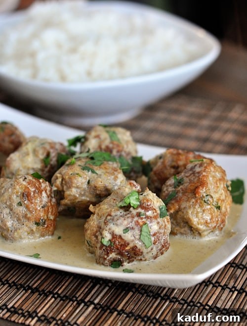 Vibrant Thai Green Curry Meatballs 3 Curry sauce and parsley covered meatballs in a white dish.