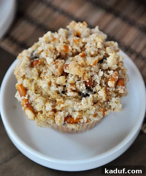 Salty Sweet Pretzel Chocolate Chip Muffins 3 Top view of a pretzel-crusted chocolate chip muffin on a small white plate, showcasing the generous and crunchy streusel topping.