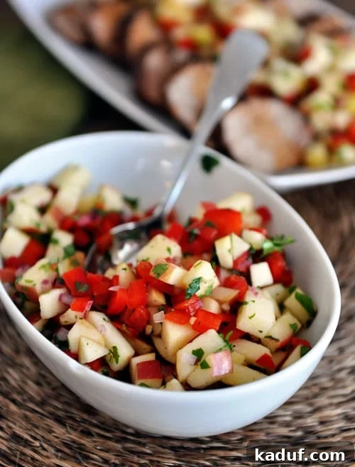 Sweet Heat Pork Tenderloin with Bright Apple Salsa 3 A white oval bowl with fresh apple salsa and sliced pork loin in the background.