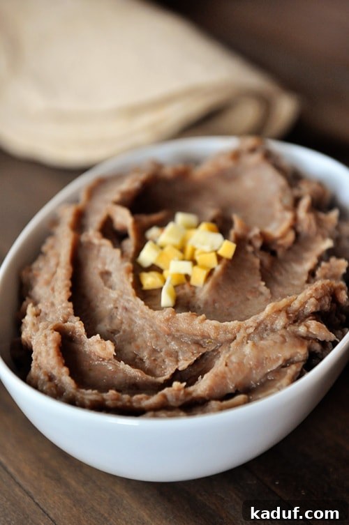 Fat-Free Slow Cooker Refried Beans 3 White oval dish full of refried beans topped with small cheese cubes.