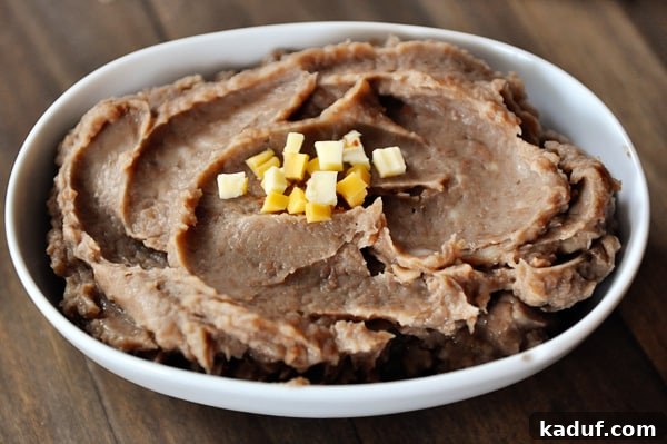 Fat-Free Slow Cooker Refried Beans 4 White oval bowl full of refried beans.