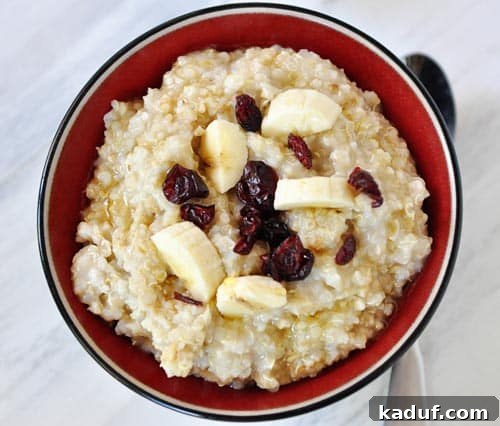 Top view of cooked steel cut oats with bananas and dried cranberries on top.