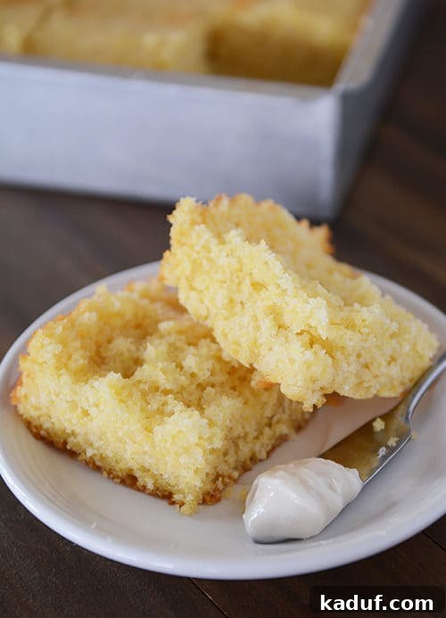 The Ultimate Cornbread with Cloudlike Honey Butter 12 A white plate featuring a perfectly split piece of cornbread, with a butter knife resting on the side, ready for spreading.