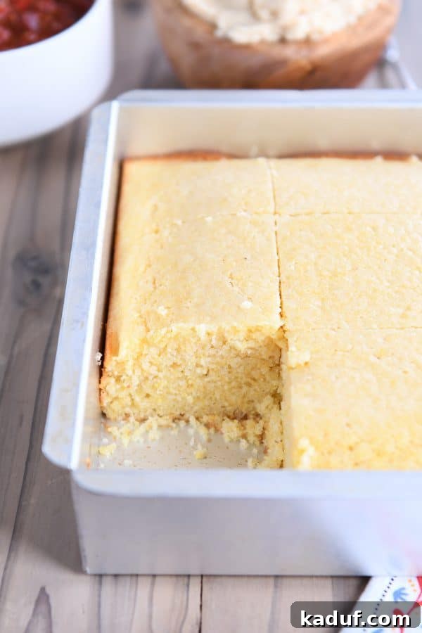 The Ultimate Cornbread with Cloudlike Honey Butter 4 A freshly baked pan of golden cornbread with one slice carefully removed, showcasing its appealing crust and texture.