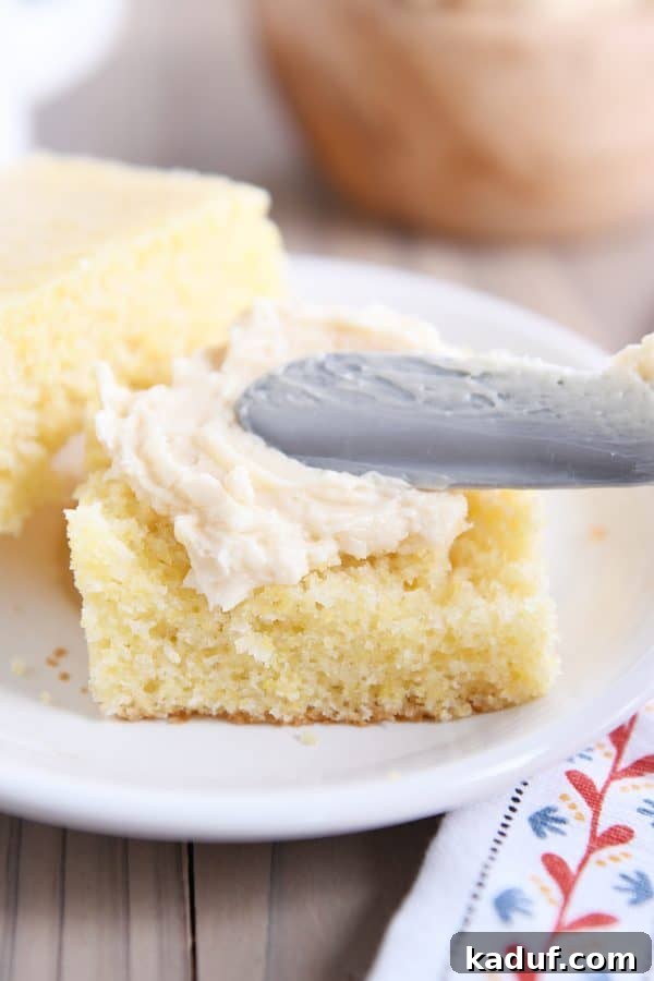 The Ultimate Cornbread with Cloudlike Honey Butter 9 A hand spreading fluffy honey butter onto a warm piece of freshly baked cornbread, highlighting its inviting texture.