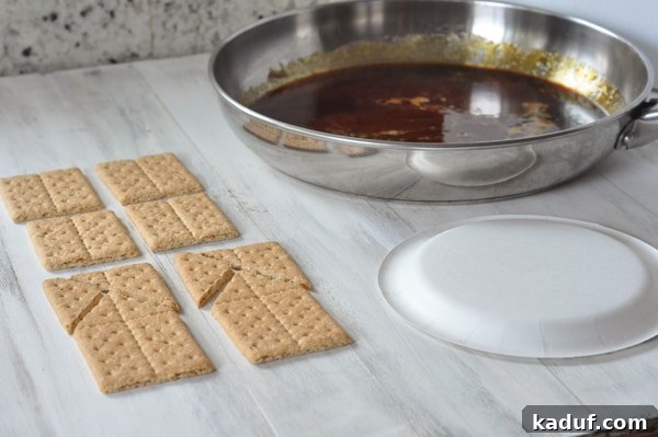 DIY Halloween Haunts 6 Graham cracker pieces, a white plate, and a pan of melted sugar laid out on a table, ready for assembly