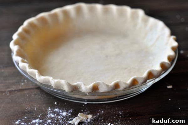 The Ultimate Pie Crust Recipe and Guide 2 Uncooked crimped pie crust in a glass pie dish, ready for baking.