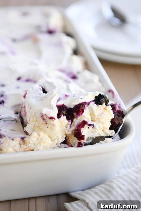 Blueberry Cream Angel Cloud Cake 2 Scooping out a serving of heavenly blueberries and cream angel food cake dessert.