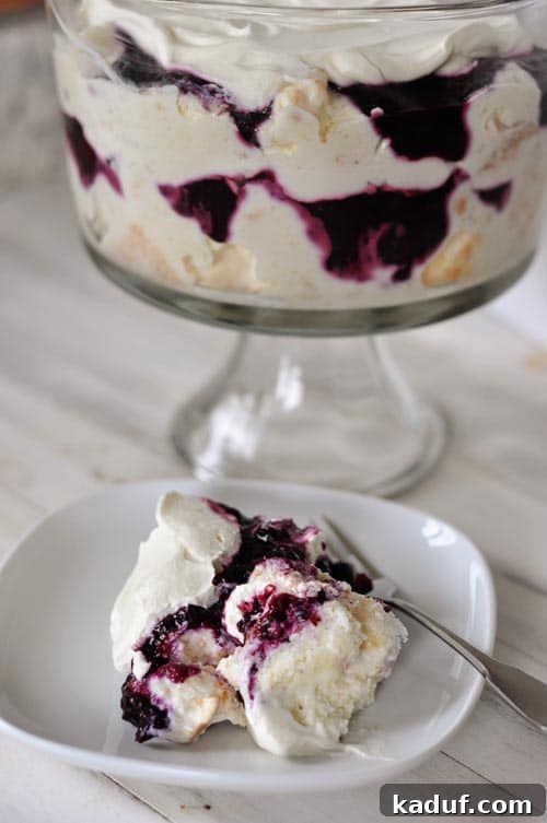 Blueberry Cream Angel Cloud Cake 10 A plate with a white cake and blueberry dessert, with a trifle dish full of the dessert in the background.