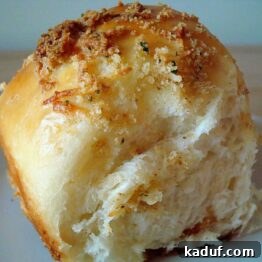 Close-up of a single cheese roll with buttery parmesan crust