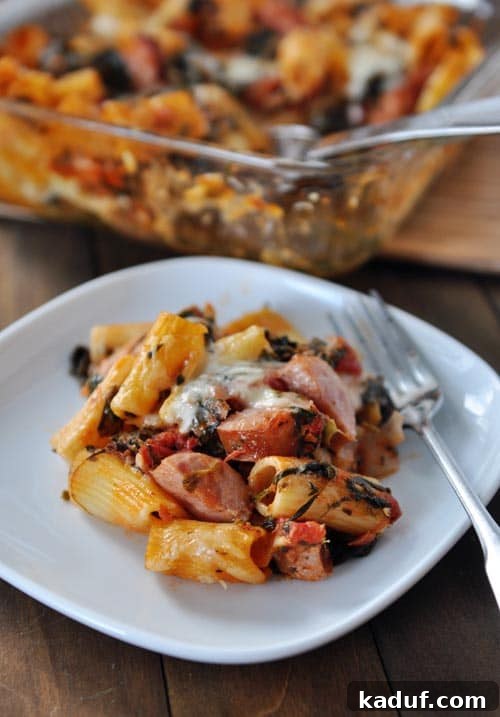 Hearty Chicken Sausage Pasta Bake 4 Baked pasta, cheese, chicken sausage, and a fork on a white plate, ready to be enjoyed.