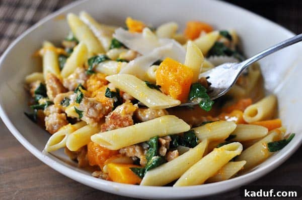Skillet Sausage and Butternut Penne 3 A serving bowl filled with creamy butternut squash, penne pasta, crumbled chicken sausage, and wilted spinach, garnished with fresh herbs.
