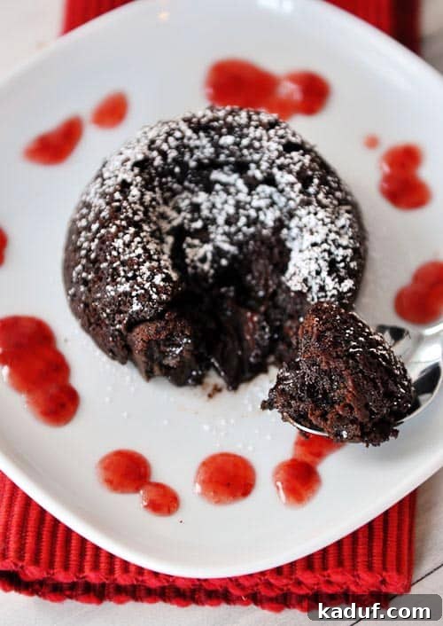 Guilt-Free Molten Chocolate Fudge Cakes 3 An overhead view of a single chocolate molten cake, elegantly sprinkled with powdered sugar, presented on a minimalist white plate, highlighting its rich, dark color and inviting texture.