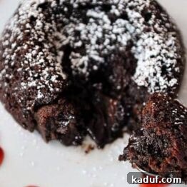 Guilt-Free Molten Chocolate Fudge Cakes 5 A close-up shot of a molten chocolate fudge cake, showcasing its rich, dark exterior and a hint of the soft, gooey interior. It's ready for a dusting of powdered sugar.