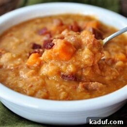 White bowl with a serving of Ham, Sweet Potato and White Bean Soup with Bacon.