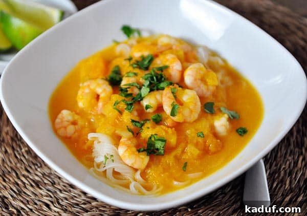 Tropical Butternut Shrimp Curry Noodle Bowl 3 A close-up view of the rich, creamy shrimp curry sauce generously poured over delicate rice noodles in a crisp white bowl, ready for a squeeze of lime.