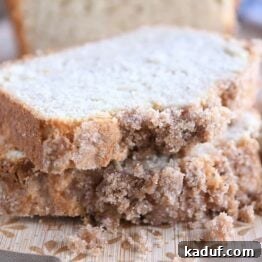 Two generous slices of cream cheese banana bread, beautifully stacked and displaying the delicious cinnamon topping and moist interior, arranged on a sturdy wooden cutting board, ready for tasting.