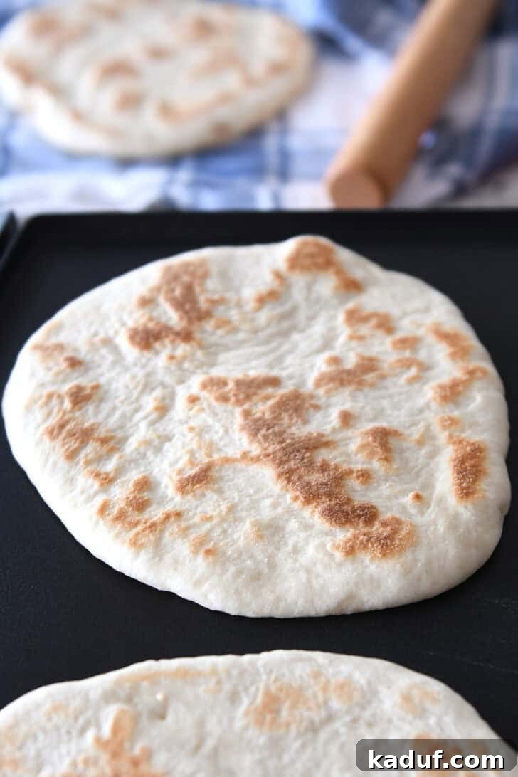 Delicious Homemade Flatbread 8 Golden brown round flatbreads getting cooked on a griddle.