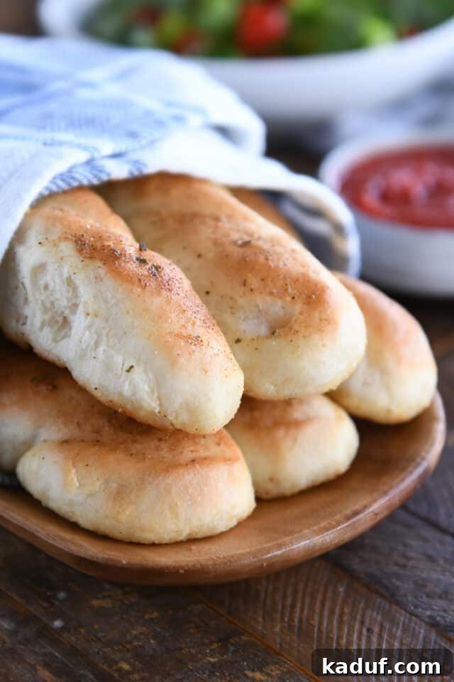 Heavenly 60-Minute Homemade Breadsticks 2 Five golden-brown homemade breadsticks artfully arranged on a rustic wooden board, ready to be served as a delicious appetizer or side dish.
