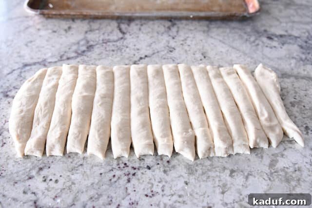 Heavenly 60-Minute Homemade Breadsticks 4 Freshly prepared breadstick dough, neatly cut into uniform strips on a clean kitchen counter, awaiting their final twist and seasoning.