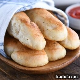 Heavenly 60-Minute Homemade Breadsticks 10 Five breadsticks on wood board with marinara sauce.