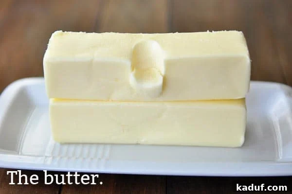 The Gold Standard Homemade Yellow Cake 5 Two sticks of perfectly softened butter, crucial for a tender and moist yellow cake, resting on a white butter dish.