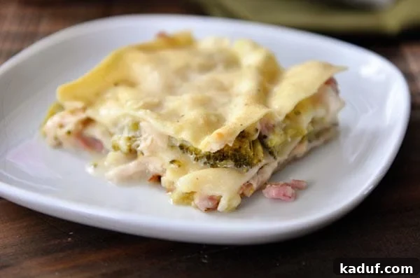 Gourmet Cordon Bleu Lasagna Bake 3 A square serving of rich Chicken Cordon Bleu Lasagna, revealing its decadent layers of creamy sauce, tender chicken, savory ham, and melted cheeses, ready to be enjoyed.