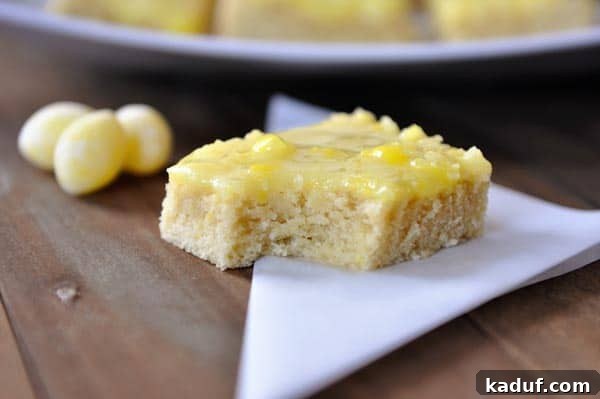 Zesty Lemon Drop Sugar Cookie Bars 3 A close-up of a Lemon Drop Sugar Cookie Bar with a bite taken out, revealing the soft cookie texture and thick glaze, surrounded by whole lemon drop candies.