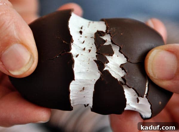 Pillowy Marshmallow Easter Eggs from Scratch 2 Hands pulling apart a chocolate marshmallow egg, revealing the soft white interior.