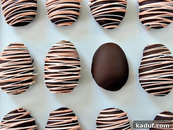 Pillowy Marshmallow Easter Eggs from Scratch 4 Top view of pink and white drizzled chocolate covered marshmallow eggs on a piece of parchment paper, arranged beautifully.