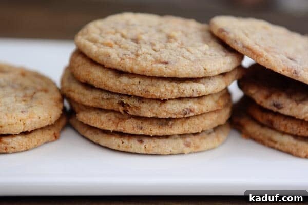 Thin Chewy Butterfinger Cookies 3 Stacks of thin butterfinger cookies on a white platter, perfectly baked and ready to be enjoyed.