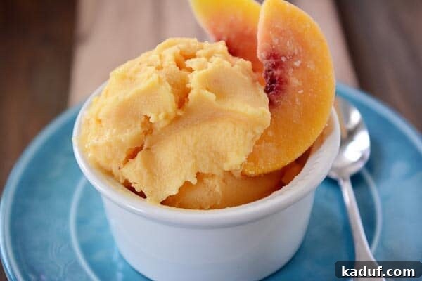 Effortless Healthy Peach Frozen Yogurt 3 A small white bowl filled with creamy peach frozen yogurt, delicately garnished with thin slices of fresh peach.