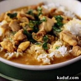 A bowl of white rice topped with chicken curry.