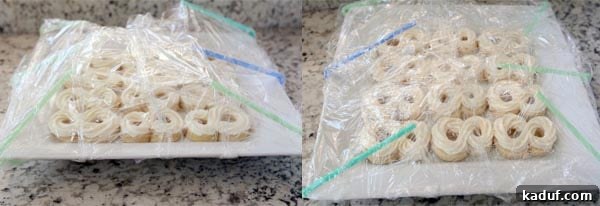 Two white platters of frosted sugar cookies are perfectly covered with plastic wrap draped over a framework of bendy straws, demonstrating the successful protection of the decorations.