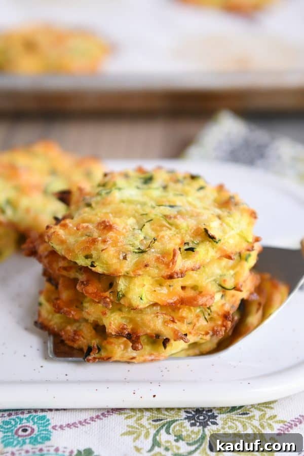 Cheesy Zucchini Gems 2 Four baked cheesy zucchini bites stacked on a spatula.