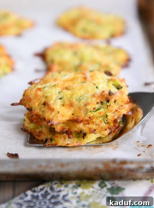 Cheesy Zucchini Gems 7 Baked cheesy zucchini bites stacked on a spatula.