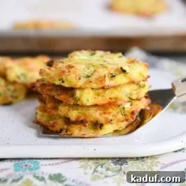 Cheesy baked zucchini bites stacked on a spatula.