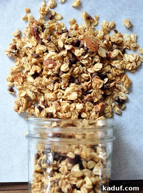 Golden Peanut Butter Clusters 2 A mason jar spilling out peanut butter granola onto a piece of parchment.