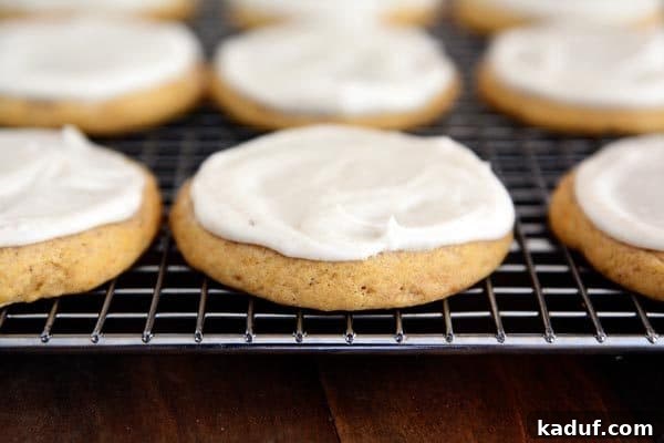 Pillowy Spiced Pumpkin Glaze Cookies 2 Frosted pumpkin sugar cookies cooling on a wire rack, showcasing their soft texture and delightful cinnamon icing – perfect for fall.