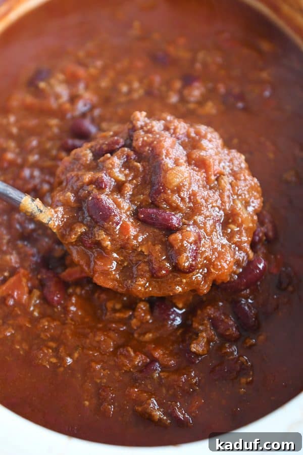 Rich & Hearty Slow-Cooked Chili 2 A ladle serving a generous portion of classic slow cooker chili, showcasing its rich texture and vibrant colors.