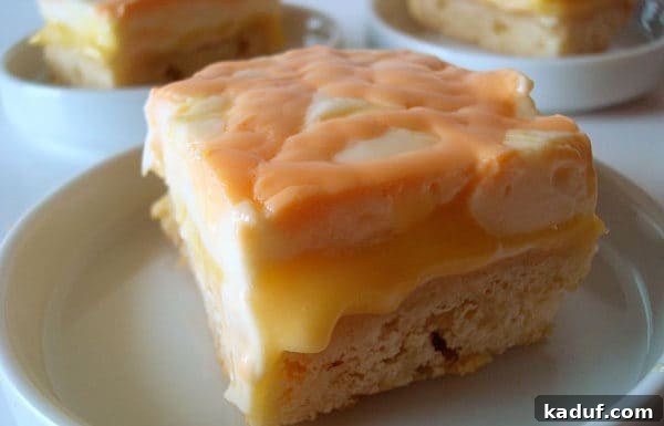 Sunshine Orange Cream Bars 3 Close-up of an Orange Cream Bar slice on a white plate, showing the three distinct layers.