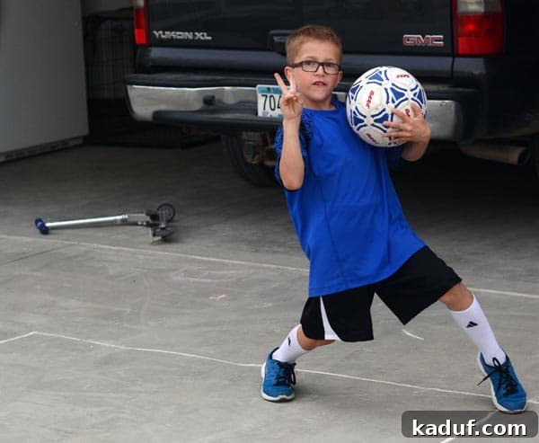 A little boy holding a soccer ball and playing outside. 