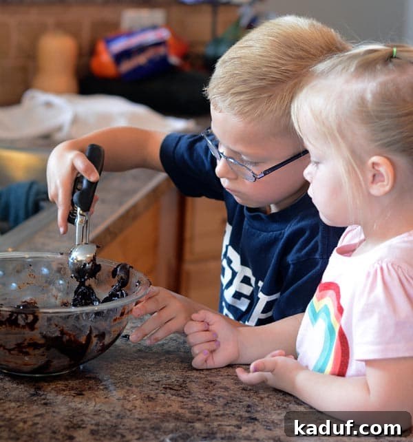 A little girl and boy scooping cookie dough together. 